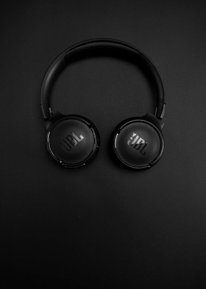 Close-up of modern black headphones on a sleek black background, showcasing minimalist tech design.